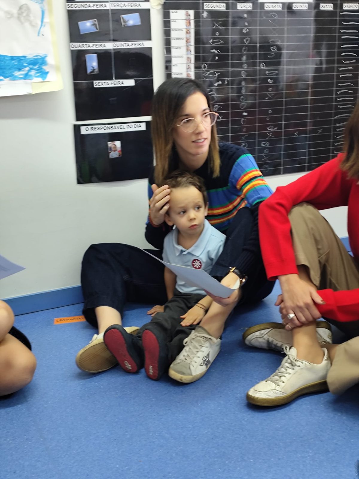 Mãe sentada no chão com o filho ao colo, a ler a história