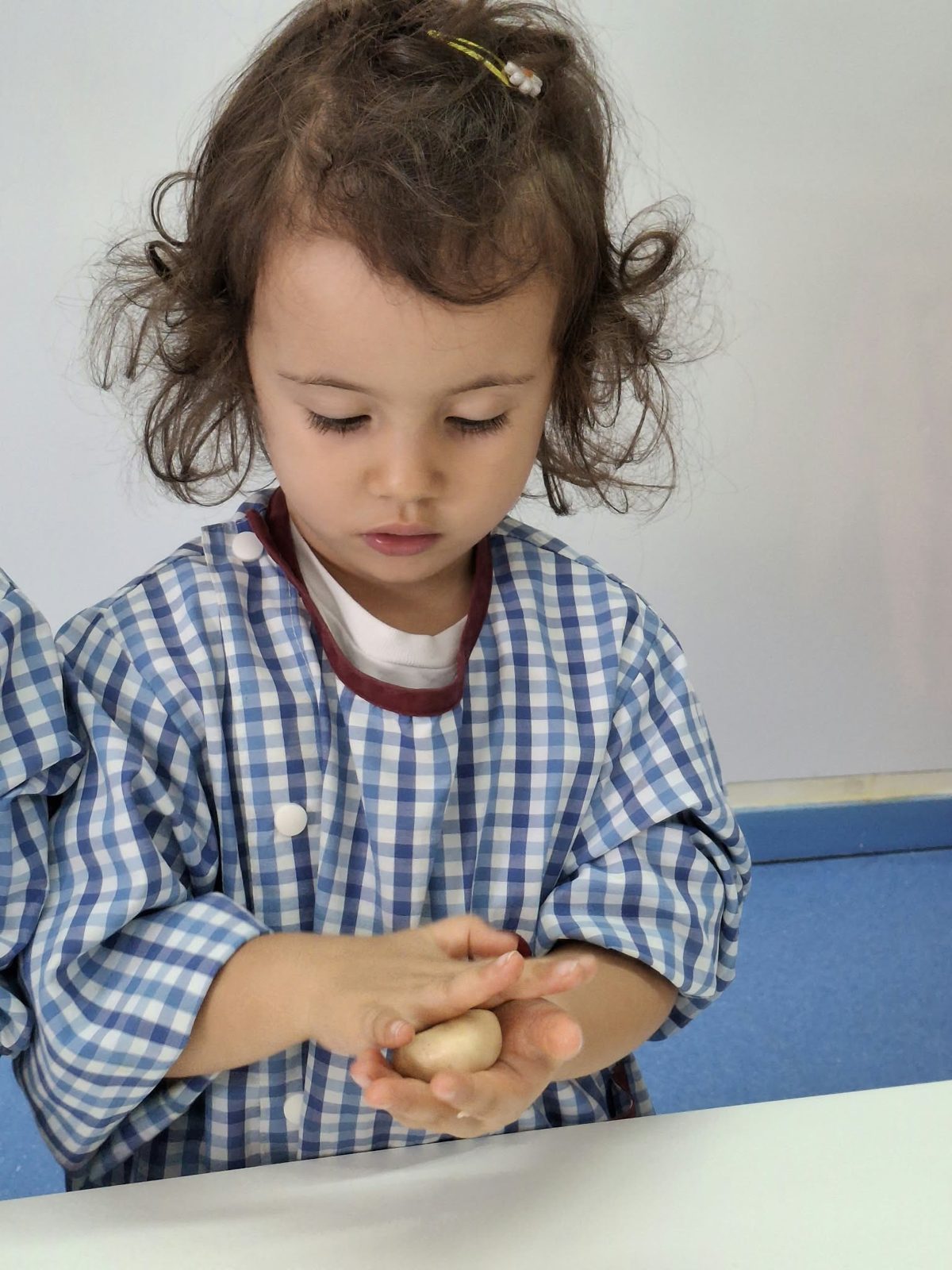 Criança a moldar uma bola de massa com as duas mãos